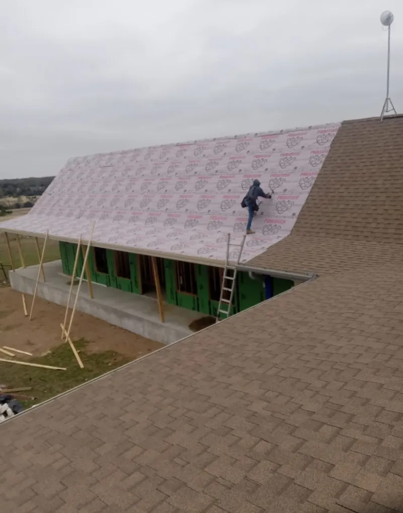 Worker preparing underlayment for a metal roof installation in La Quinta